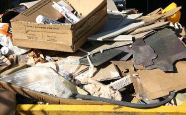 UK yellow builders skip with construction waste — photo Si Griffiths, Wikimedia Commons, CC BY-SA 3.0 (File:Skip_UK.jpg)